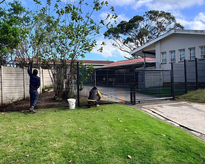 Two of the New Age Fencing team working on a fence in front of a house